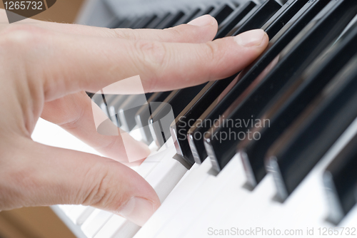 Image of hand playing music on the piano