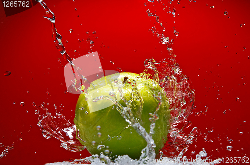 Image of Green apple with water splash on red background