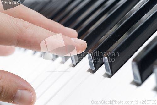 Image of hand playing music on the piano