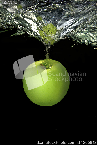 Image of green apple dropped into water with splash isolated on black