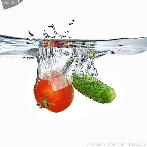 Image of red tomato and green cucumber dropped into water isolated on whi