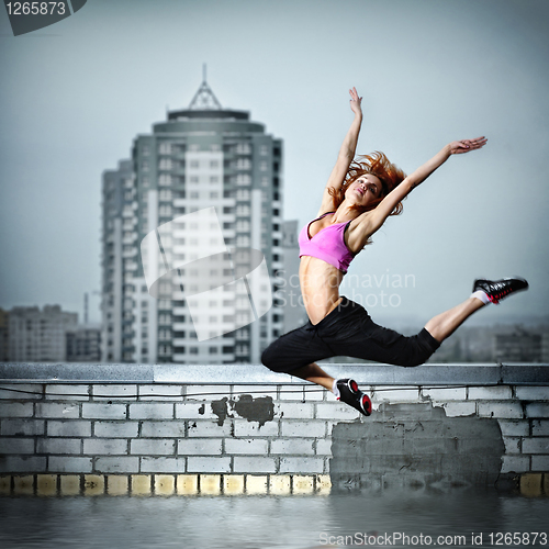 Image of girl humping on the roof against city background