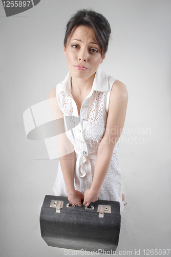 Image of begging brunette with travel bag in white dress