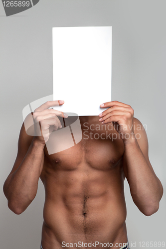 Image of Muscular naked man holding white empty paper