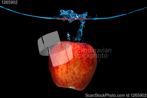 Image of red apple dropped into water with splash isolated on black