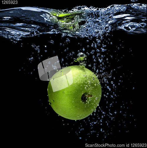 Image of green apple dropped into water with splash isolated on black