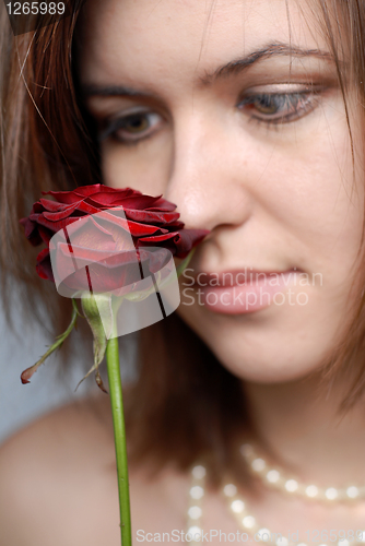 Image of color portrait of woman looking at red rose