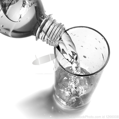 Image of water pouring into glass from bottle isolated on white