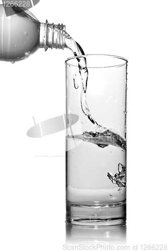 Image of water pouring into glass from bottle isolated on white