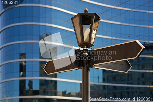 Image of Blank signpost with ancient lamp against business building