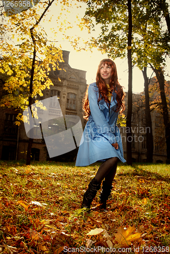 Image of Woman in blue jaket posing in autumn park