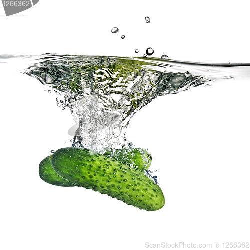 Image of green cucumbers dropped into water isolated on white