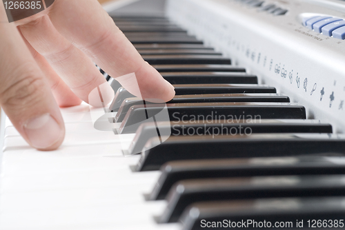 Image of hand playing music on the piano