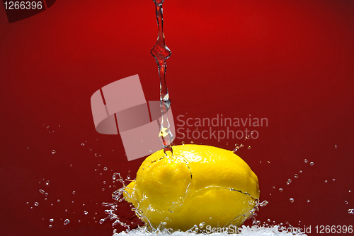 Image of Fresh lemon and water splash on red