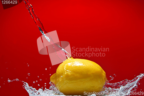 Image of Fresh lemon and water splash on red