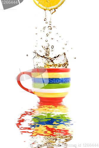 Image of Lemon juice and splash of tea in color cup with reflection