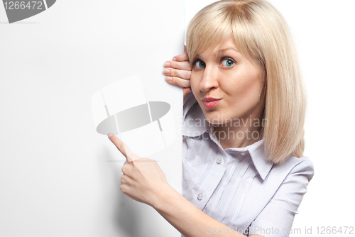Image of Attractive smiling woman holding white empty paper and pointing 