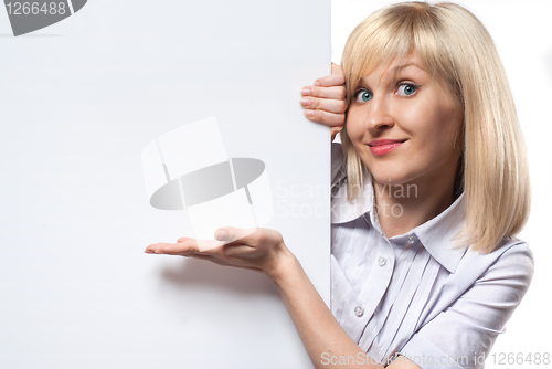 Image of Attractive smiling woman holding white empty paper and pointing 