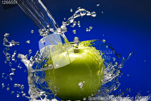 Image of Green apple with water splash on blue background