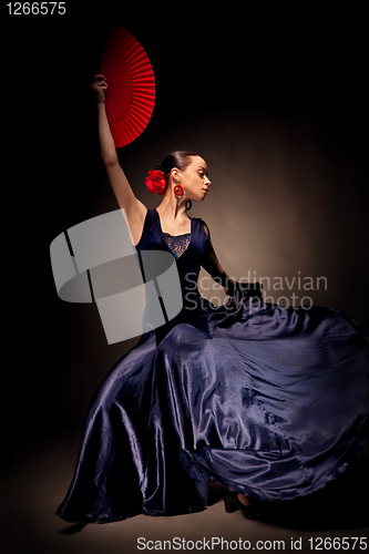 Image of young woman dancing flamenco on black