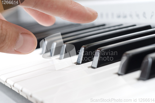 Image of hand playing music on the piano