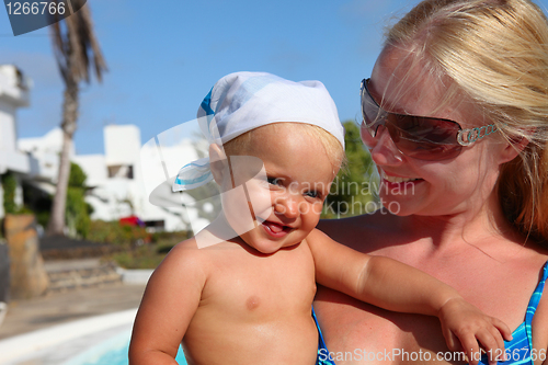 Image of portrait of smilling mother and daughter near pool. Focus on the