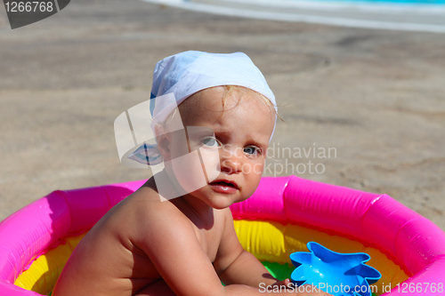 Image of baby girl playing in a colorful kiddie pool