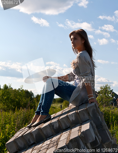 Image of beautiful girl sitting on the ruins