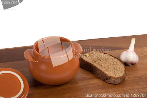 Image of Soup in clay pot on wooden table