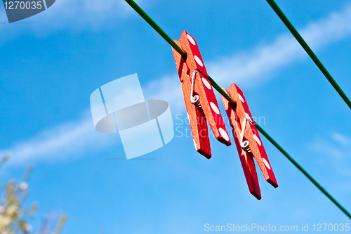 Image of Two red clothes pegs against a bright blue sky