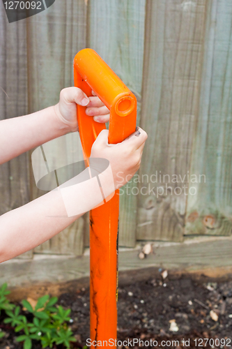 Image of Child's hands holding the handle of a garden spade
