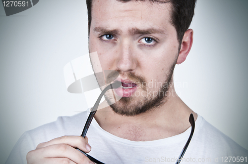 Image of Young man holding sunglasses