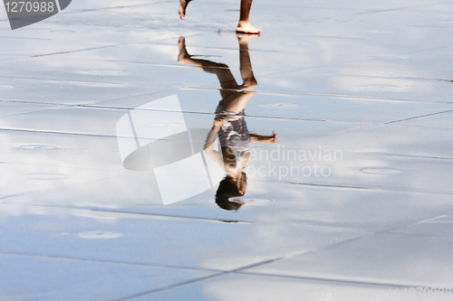 Image of Reflection of a child running in the water.