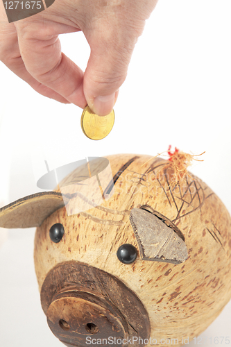 Image of Saving, male hand putting a coin into piggy bank. 