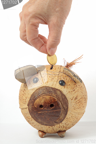 Image of Saving, male hand putting a coin into piggy bank. 