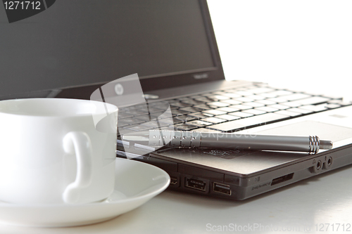 Image of A cup of coffee and a pen on a laptop 