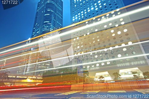 Image of traffic light trails in the street by modern building