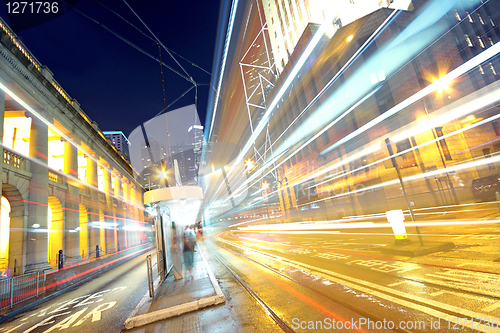 Image of traffic light trails in the street by modern building