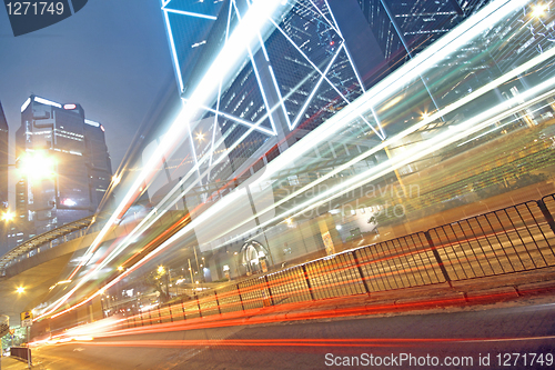 Image of traffic light trails in the street by modern building