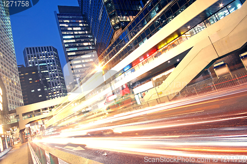 Image of traffic light trails in the street by modern building