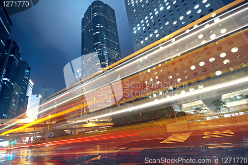 Image of traffic light trails in the street by modern building