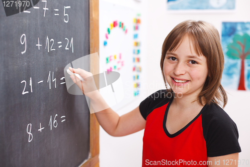 Image of School girl writing solution on chalkboard