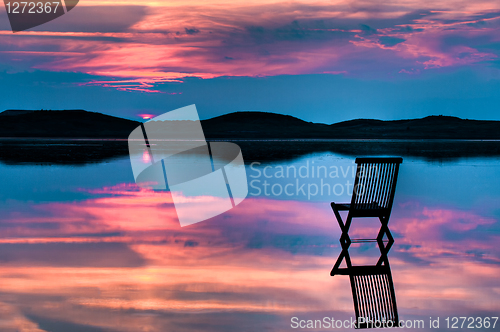 Image of Scenic view of sunset over inlet and hills with a chair in the c