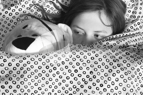 Image of young girl in bed holding teddy bear