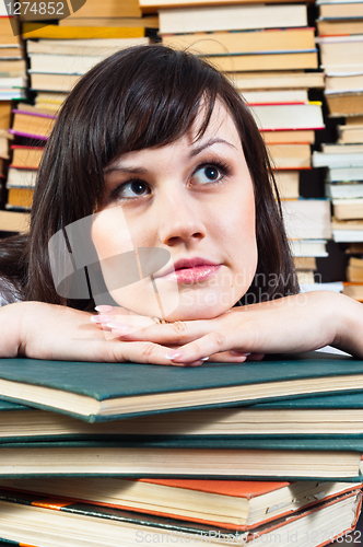 Image of Young student girl daydreaming on books