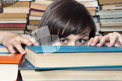 Image of Young beautiful student girl behind books