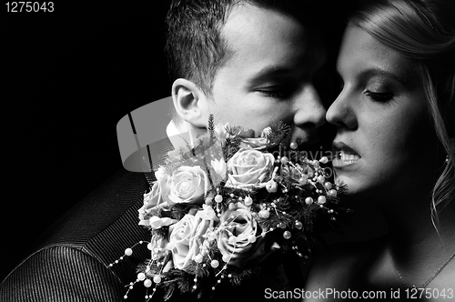 Image of young couple in wedding wear with bouquet of roses 