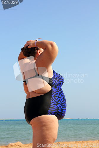 Image of overweight woman on beach with hands up