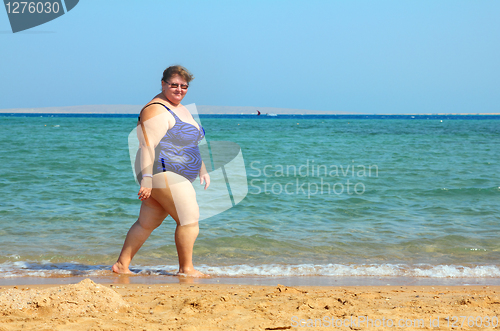 Image of overweight woman walking on beach