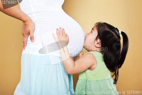 Image of Girl kissing pregnant mother